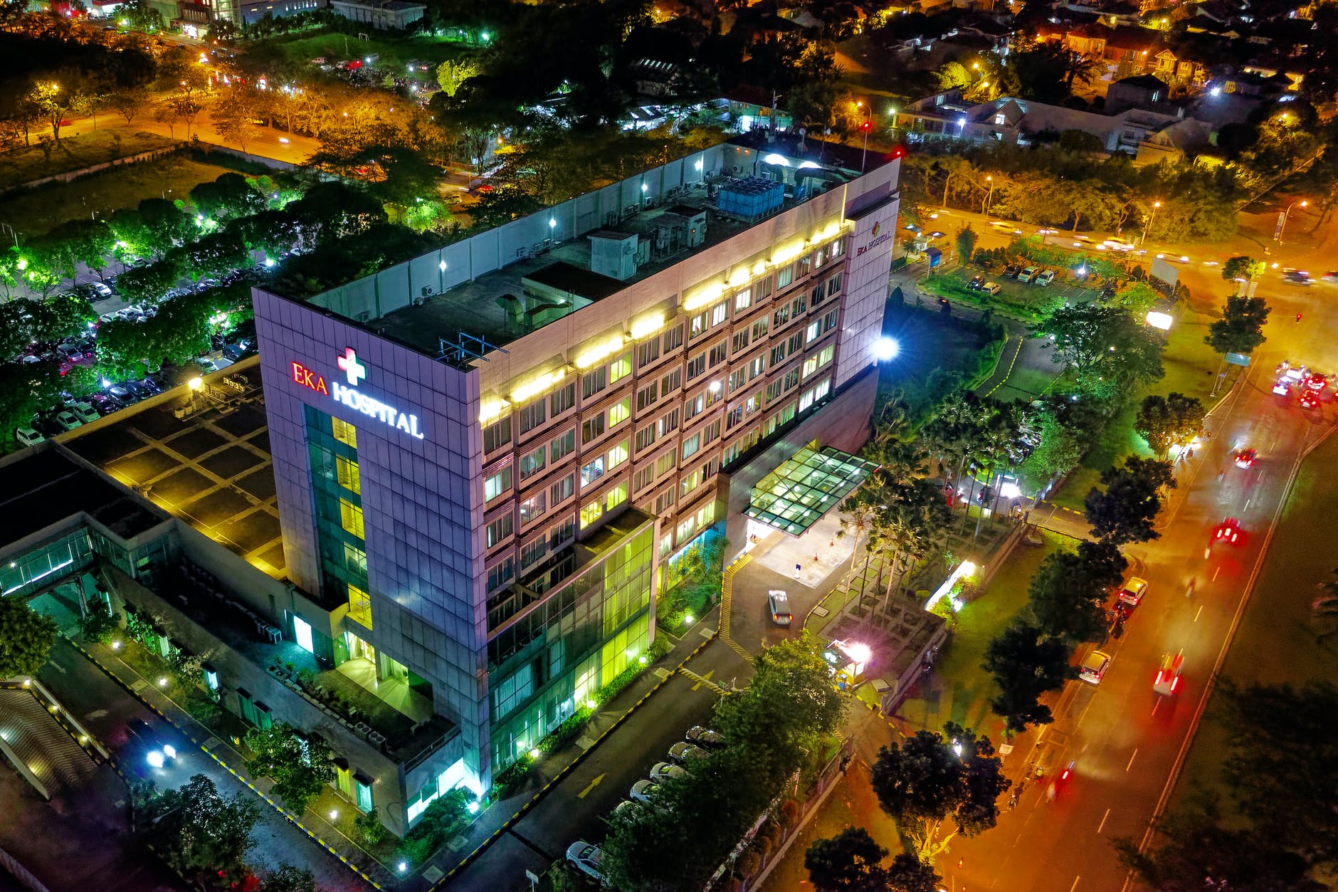 hospital beside vehicle park and road at night